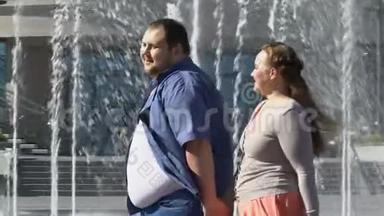 快乐的超重夫妇在喷泉旁<strong>散步</strong>，<strong>牵手</strong>，肥胖问题