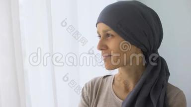 戴头巾的快乐女人看着窗外，癌症治疗后恢复