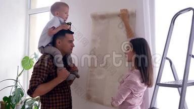 幸福的一家人在新家做修理，幸福的爸爸妈妈和儿子肩上扛着肩选择了公寓的壁纸