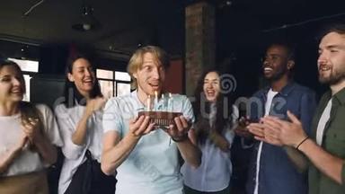 一个满脸表情的大胡子正在许愿，在生日蛋糕上吹蜡烛，而他的同事们正在鼓掌