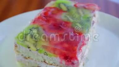 水果蛋糕上有猕猴桃和草莓，果冻放在白色盘子里，旋转成一圈