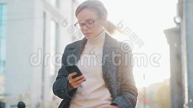 一个手里拿着智能手机的年轻女人的肖像。 女孩在户外使用手机