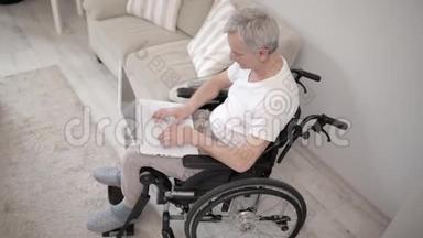 灰头土脸的男人坐在他的病房里的轮椅上，坐在笔记本电脑前。