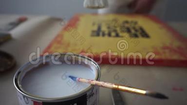 这位艺术家把刷子浸入罐子里。 用清漆覆盖图片。 油漆罐。 你这个胆小鬼。 手工艺