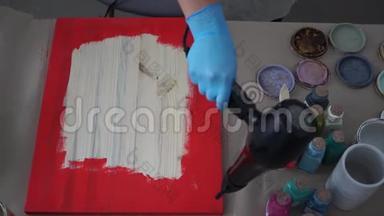 女孩用吹风机在围裙和手套上擦干一张照片。 油漆罐