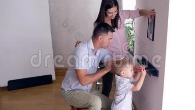 在公寓<strong>搬迁</strong>后，可爱的孩子帮父母把架子栓到墙上