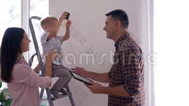 年轻的家庭在新公寓的室内装修中很开心，开朗的父亲和儿子、妻子亲吻丈夫