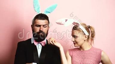 有胡子的男人有耳朵，兔子和金发女人有耳朵，兔子在粉红色的背景上吃苹果。 有兔子耳朵的女人
