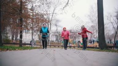 一位年老的妇女发出手势，两位老年妇女开始用北欧的拐杖走路。 慢动作