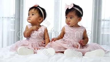 两个穿着粉红色裙子的<strong>双胞胎宝宝</strong>躺在床上，一个在看，一个在哭