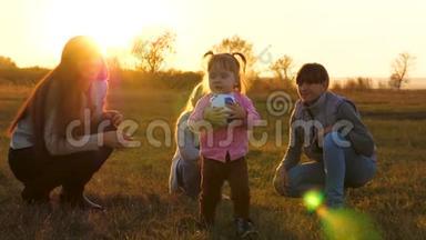 孩子正在场地上用明亮的阳光捧着足球。 快乐的小女孩和妈妈和姐妹一起<strong>打球</strong>。 家庭