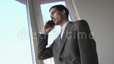 成功的商人在全景窗口附近谈论手机。 3840x2160