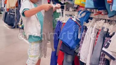 小顾客男孩在打折时挑选时装店的新衣服