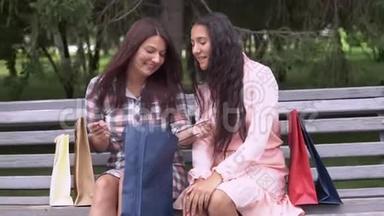 两个女孩购物后讨论在公园的长凳上购物。 慢动作。 <strong>高清高清</strong>