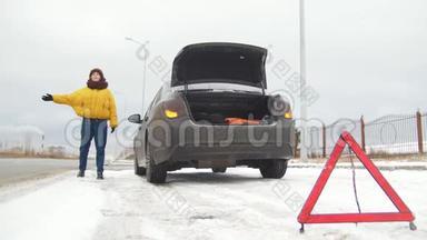 汽车故障。紧急信号。下雪的乡间公路上的汽车故障。一个年轻女子试图赶上汽车