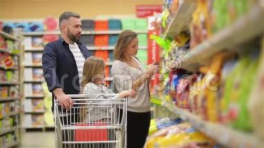 在超市：三口幸福家庭，手牵手，走过商店的新鲜农产品部分。 父亲