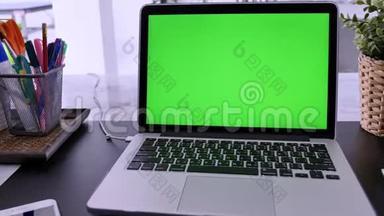 在客厅的办公桌上展示绿色彩色钥匙屏幕的笔记本电脑。 在背景舒适的客厅里。 多利动物园