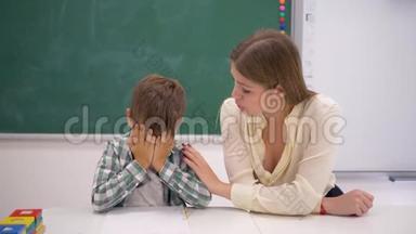 教育工作者在<strong>课外活动</strong>中，在教室黑板旁的书桌旁安抚哭泣的学童