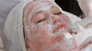 美容院的理疗程序。 一个女人接受皮肤提升的电泳。 美容师把点放在脸上