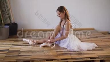 芭蕾舞女将他们的鞋子换成特殊的芭蕾舞鞋，白色的尖鞋，带芭蕾舞丝带的花边。 年轻的芭蕾舞演员
