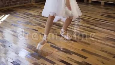 年轻的芭蕾舞演员穿着<strong>白色</strong>的芭蕾<strong>舞鞋</strong>和裙子在木地板上练习芭蕾舞。 年轻的芭蕾舞演员