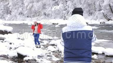 美丽的<strong>女孩</strong>穿着冬天的夹克和帽子，为摄影师摆姿势，冰肆虐的冬季河流<strong>雪景</strong>。