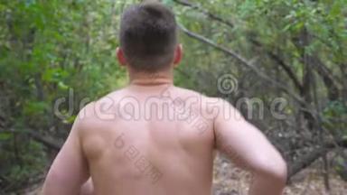 年轻的肌肉男在初秋的森林里沿着小径奔跑。 无法辨认的运动员在大自然的道路上冲刺