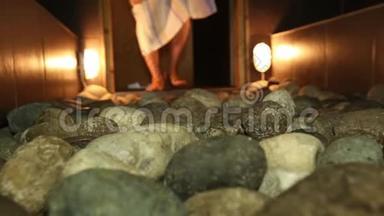 桑拿浴室里的热石头和<strong>一桶水</strong>特写男人`脚。