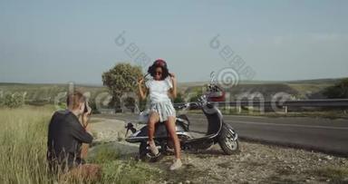 一位留着卷发的拉丁女孩正骑着摩托车为男友摆姿势
