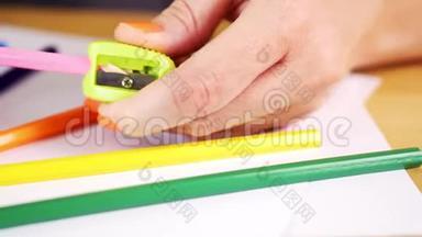 一个女人拿着一把卷<strong>笔刀</strong>和一支彩色铅笔在一张木桌上