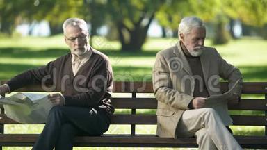 两个被冒犯的老人看报纸，坐在公园的长凳上，吵架