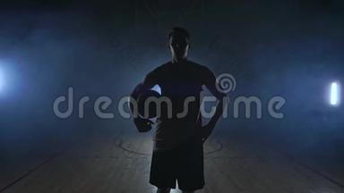 篮球<strong>运动</strong>员走到<strong>摄像机</strong>前，把球敲在地上，然后停下来，拿着球看着