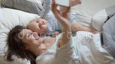 妈妈和宝宝在床上自拍。 母亲节，母爱，母亲的幸福