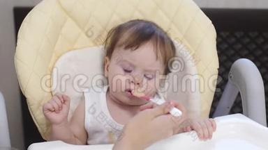妈妈用勺子喂小宝宝吃土豆泥.. 婴儿弄脏的食物衬衫。