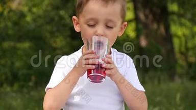孩子拿着一个<strong>杯</strong>子，里面放着一<strong>杯</strong>鲜红色的浆<strong>果汁</strong>，在大自然的背景下喝着.. 快关门。