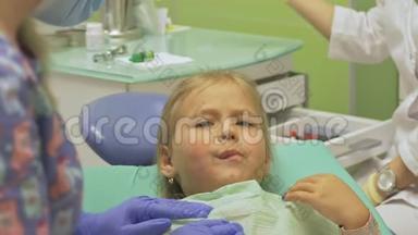 带着一个母亲的孩子在牙医`<strong>接待处</strong>。 女孩躺在椅子上，在她母亲的身后。 医生和一个