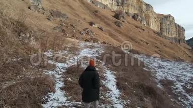 穿着<strong>羽绒服</strong>和帽子的女游客在岩石峡谷的初冬沿着小径散步。 黄色的草和碎片