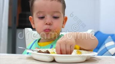 可爱的小孩子坐在围兜里的一张桌子上吃自己的肉泥，孩子吃得很心甘情愿。 可爱的小宝宝吃东西