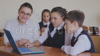 老师帮助学生在笔记本电脑上完成任务。 计算机课上的课。