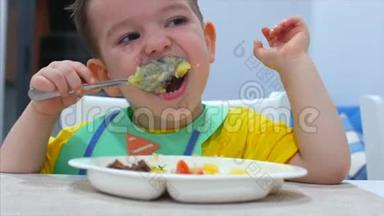 可爱的小孩子坐在围兜里的一张桌子上吃自己的肉泥，孩子吃得很心甘情愿。 可爱的小宝宝吃东西