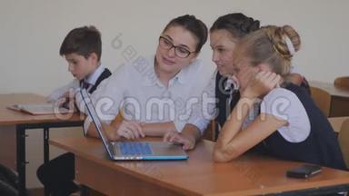 老师帮助学生在笔记本电脑上完成任务。 计算机课上的课。
