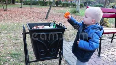 一个小男孩在街上的垃圾桶里扔垃圾。 <strong>废物管理</strong>和环境保护的理念.. 适当的做法