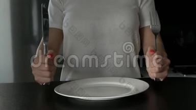 这个女孩用刀叉从盘子里拿出药丸。 减肥的概念与药丸或定期使用药丸