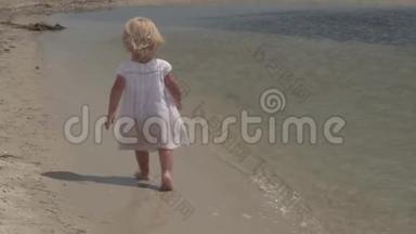 美丽的小女孩沿着海滨奔跑。 在海岸穿白色裙子的小女孩。 慢动作。