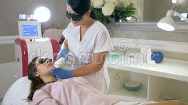 美容医生用激光设备在水疗中心的治疗室对病人面部进行脱毛
