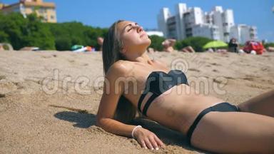 穿比基尼的年轻女孩躺在<strong>海边</strong>和日光浴的肖像。 美丽的白种人女人在<strong>海边</strong>放松