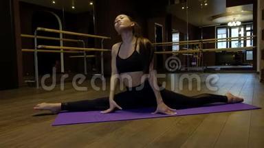 健康的亚洲女人在家锻炼，在黑暗的舞蹈室里练习伸展运动健身锻炼