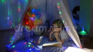<strong>家庭娱乐</strong>，快乐的孩子与爸爸进入有趣的假发阅读书在手电筒躺在神奇的帐篷与神奇的帐篷