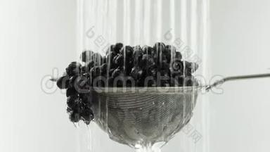 在视频中，我们看到葡萄在筛子中，水从顶部落下，在视频的末尾，水停止了，白色的背景