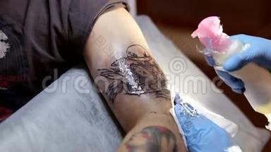 纹身师在男人手臂上做`纹身。